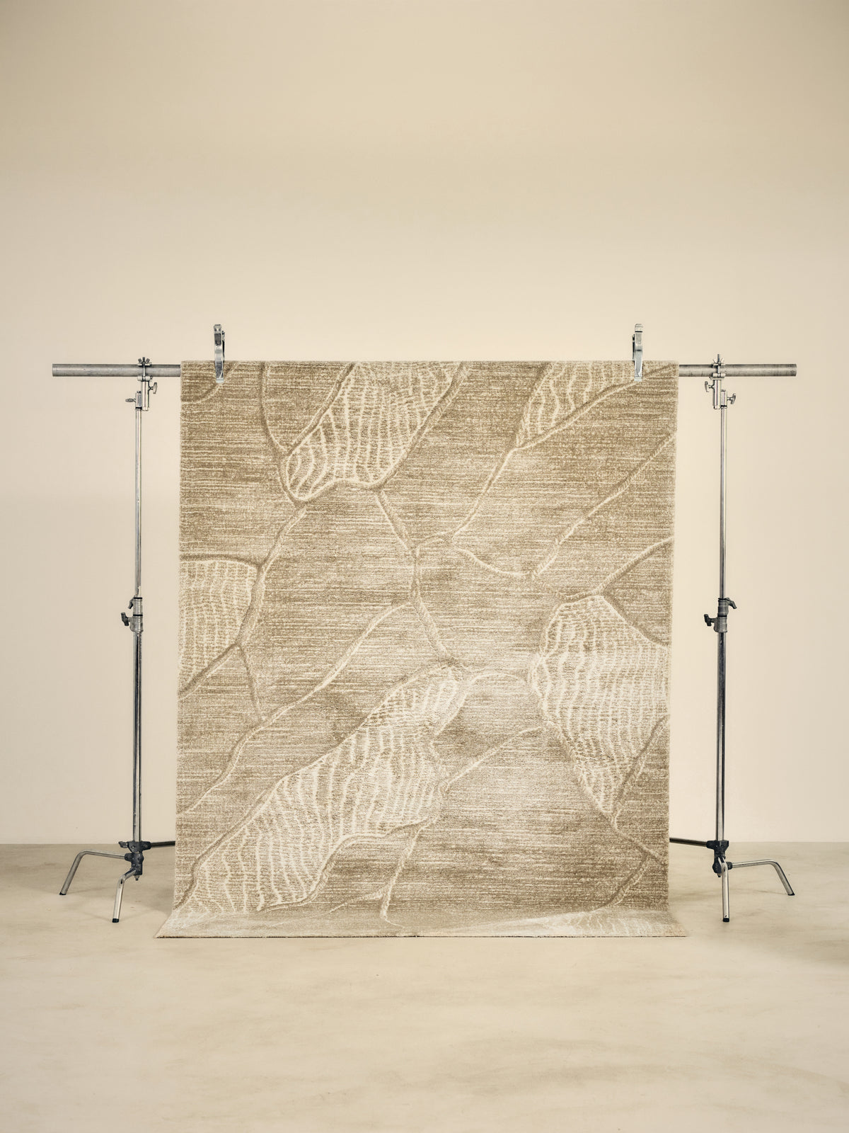 tapis de salon Folio beige à feuilles en relief ton sur ton suspendu sur un portant