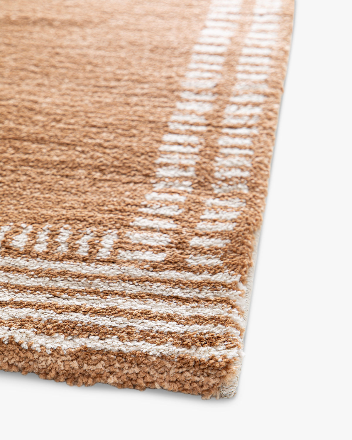 gros plan sur les rangs de tirets écrus qui encadrent un tapis de salon Haven caramel