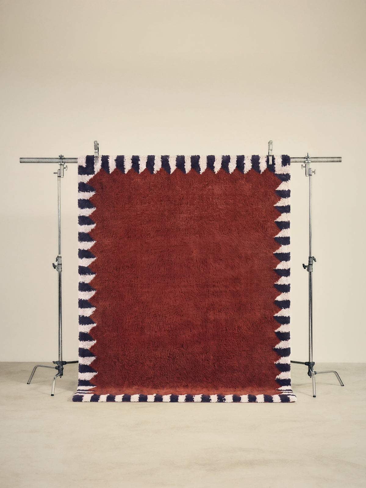 tapis ARDMORE grand format, rouge brique bordé de triangles bleus et écrus, sur un portant