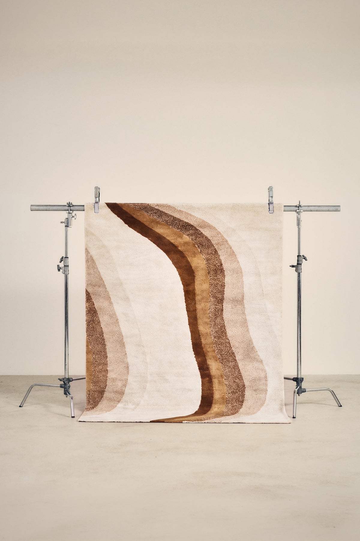 tapis LEVANTE petit format, écru à vagues brunes et caramel, sur un portant de studio