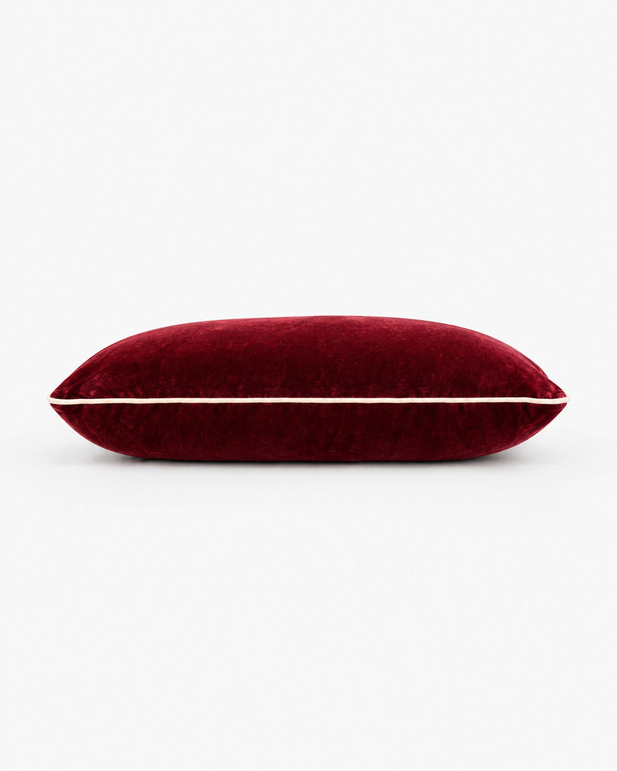 coussin rectangulaire LODGE en velours rouge bordeaux vu de profil, passepoil écru sur la tranche