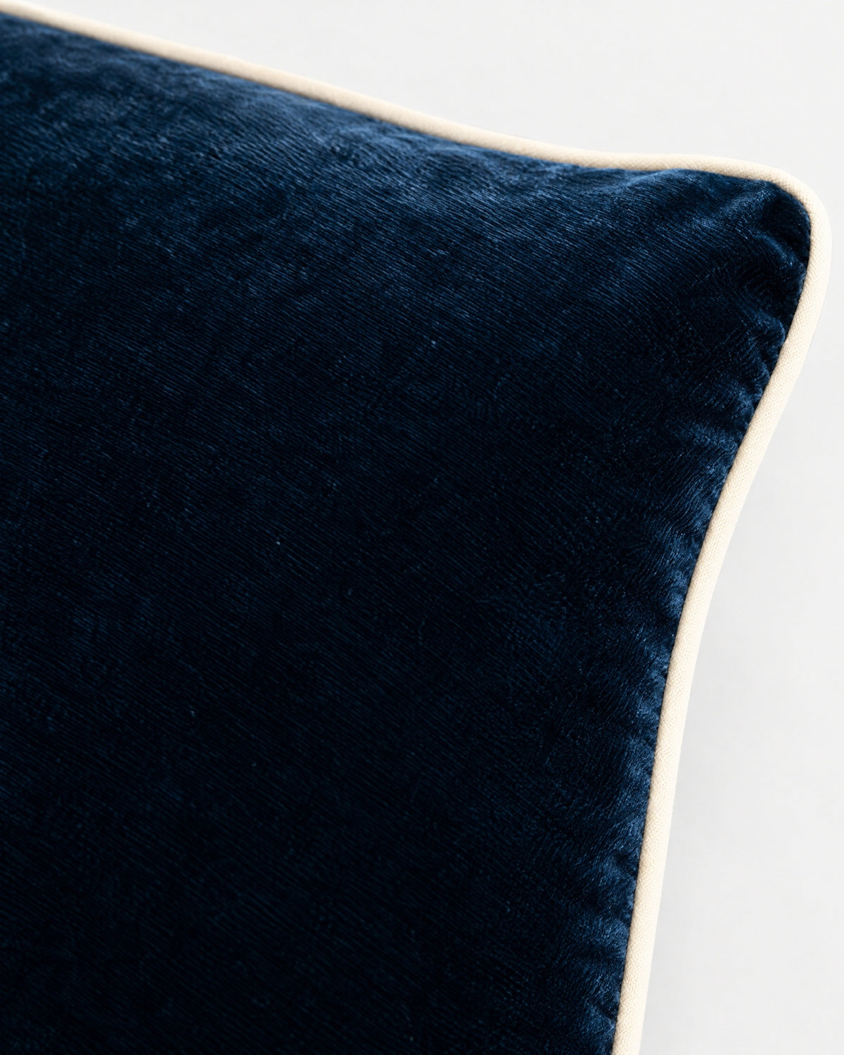 gros plan sur le passepoil écru et la texture du velours bleu nuit du coussin LODGE